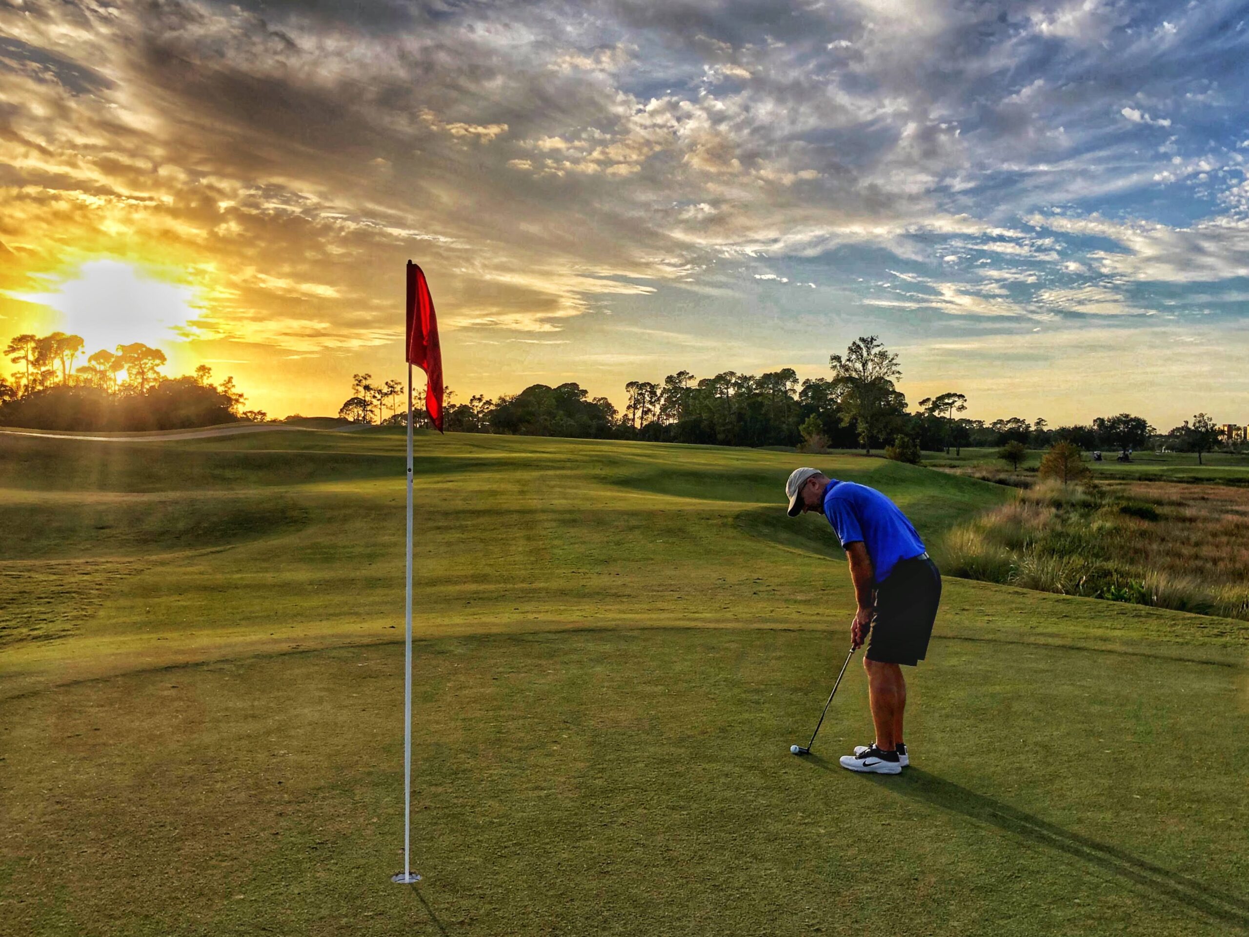 golf putt on the green with a setting sun in the background