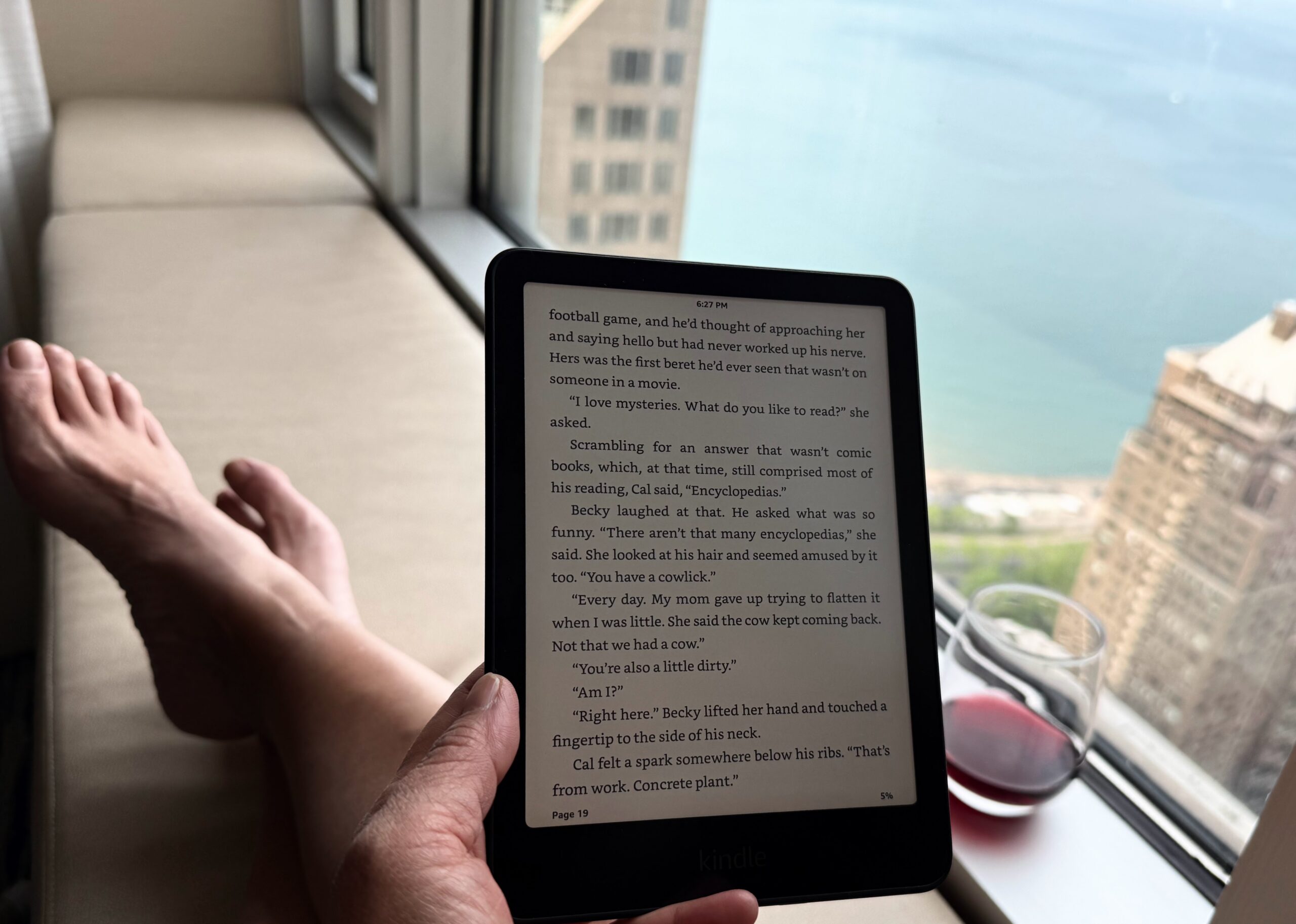 Reading a Kindle by a hotel bay window overlooking Lake Michigan in Chicago.